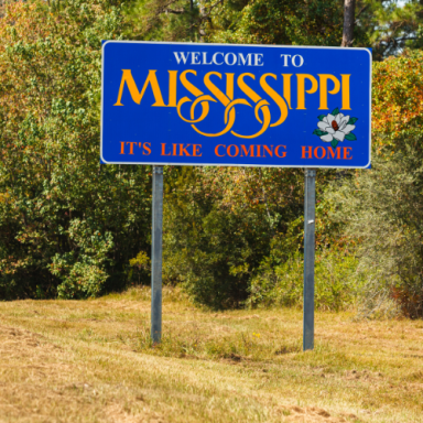 Welcome sign for Mississippi, stating "It's like coming home" with a floral emblem.