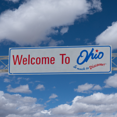 Welcome to Ohio sign with blue sky and clouds in the background.