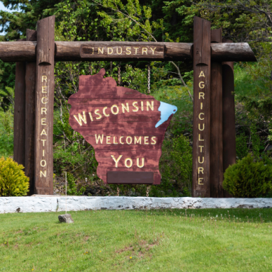 Wooden welcome sign for Wisconsin highlighting industry, recreation, and agriculture.