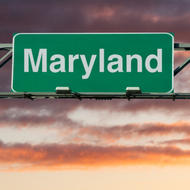 Sign for Maryland against a colorful sunset sky.