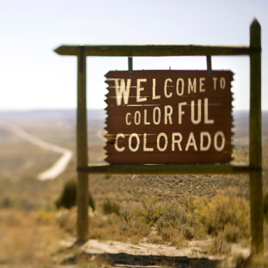 Welcome sign for Colorado against a distant landscape, emphasizing "Colorful Colorado."