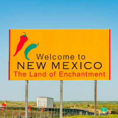 Welcome sign for New Mexico featuring chili peppers and "The Land of Enchantment."