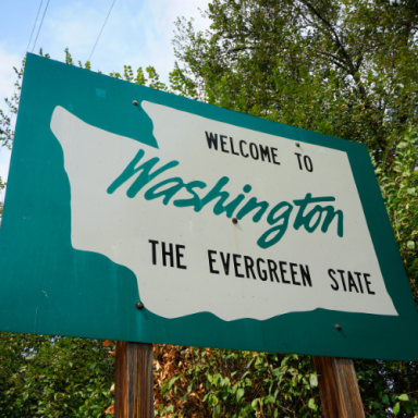 Welcome sign for Washington, labeled "The Evergreen State," with greenery in the background.