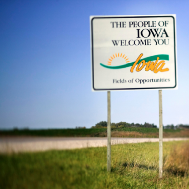 Welcome sign for Iowa, featuring a sun design and the phrase "Fields of Opportunities."