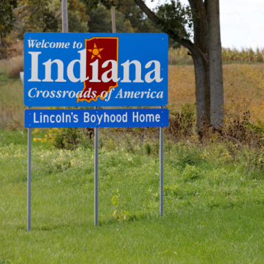 Welcome sign for Indiana, noting Lincoln's Boyhood Home amid grassy surroundings.